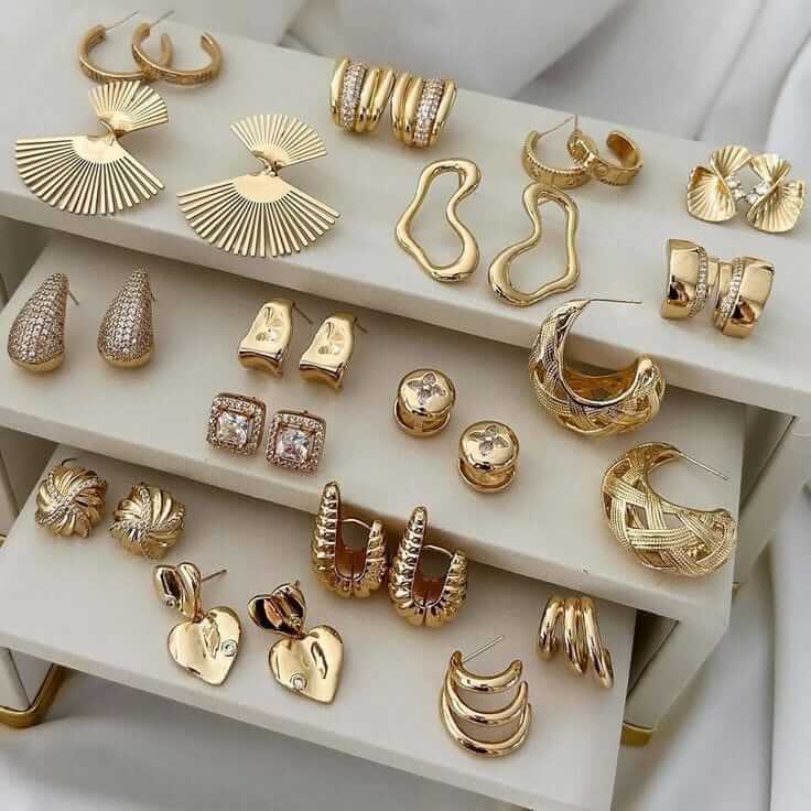 A stylish display of various gold earrings arranged elegantly on a jewelry stand, showcasing unique designs and textures.