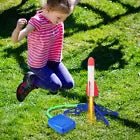 Child jumping in excitement by an air-powered rocket launcher in a grassy yard, ready for outdoor fun.