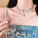 LATS Blue Crystal Butterfly Necklace with dual-layer choker design worn elegantly with a drink in hand.