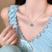 LATS blue crystal butterfly necklace worn by a woman in a light blue ruffled outfit, showcasing elegance and charm.